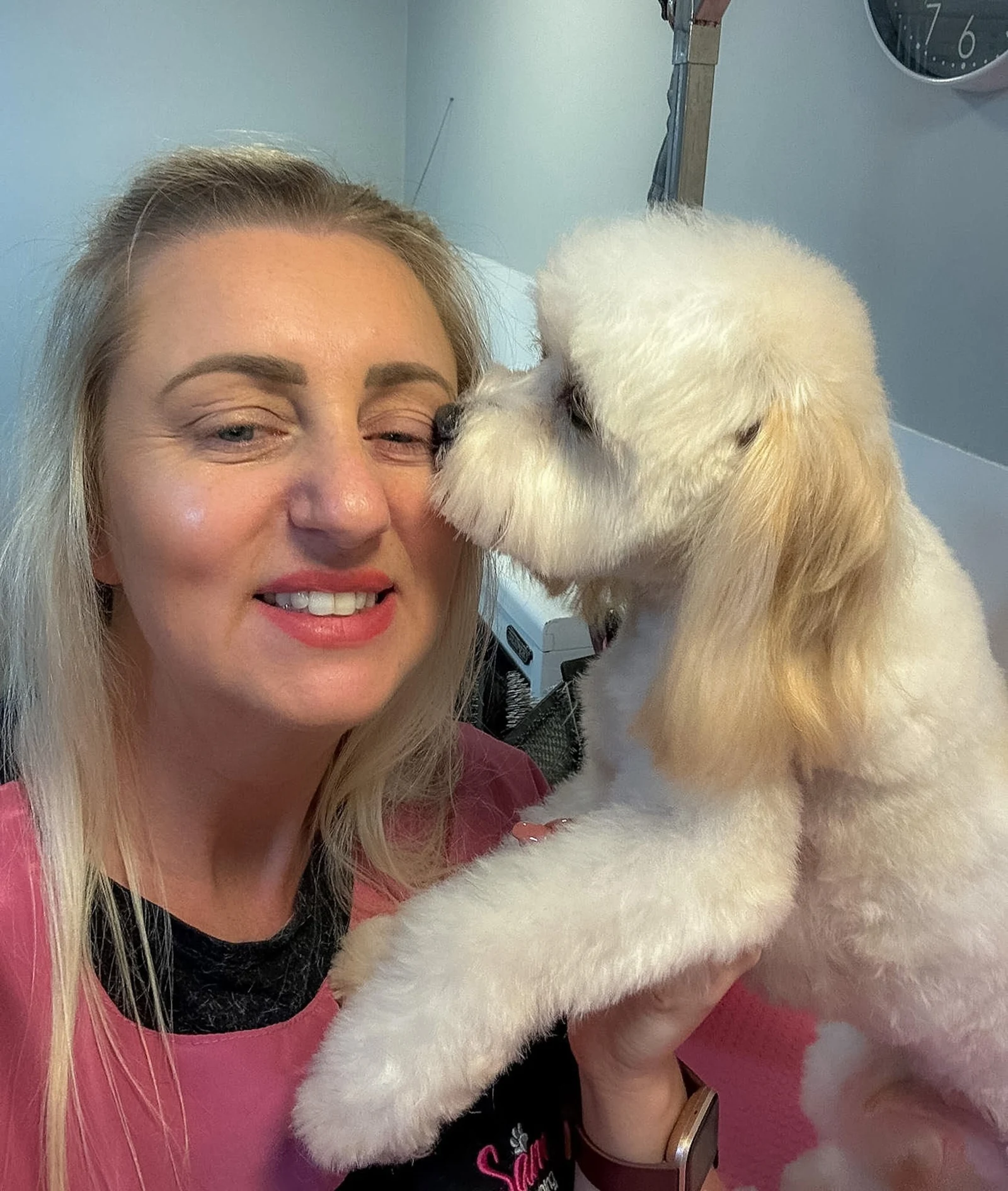 Groomer cuddling a small white dog